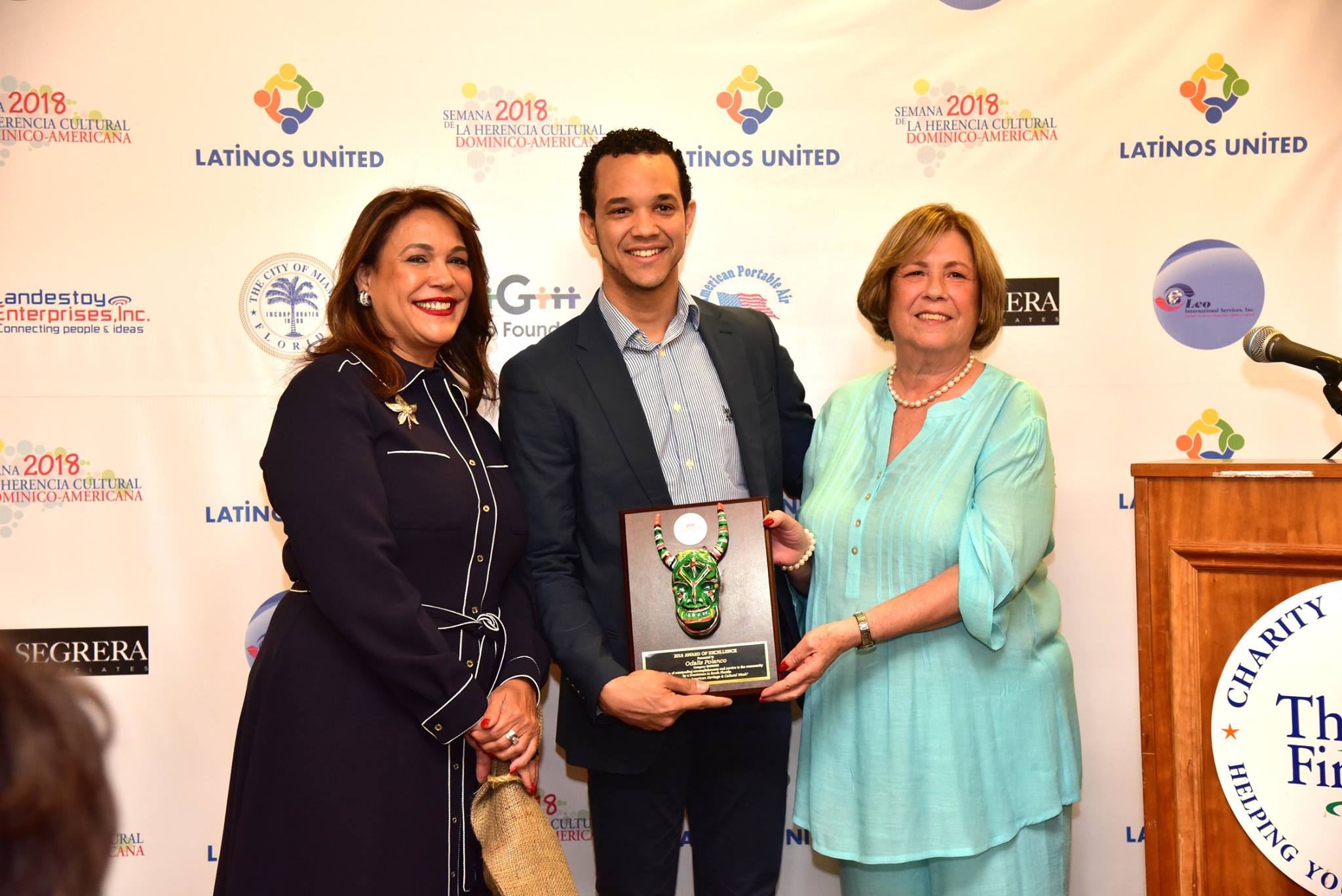 El joven Odalis Polanco ejecutivo de Well Fargo al centro, recibe su reconocimiento de manos de de la vicec&oacute;nsul Solangel Santana (izq.) y de la Dra. Amada Vargas, directora ejecutiva de Latinos Unidos.